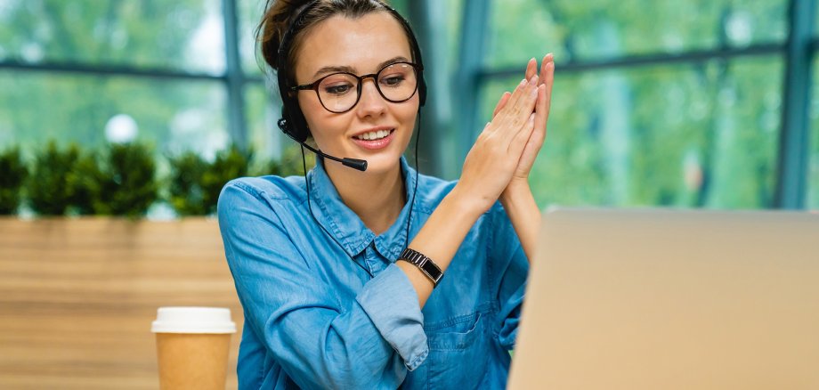 Good-looking caucasian girl talking on her laptop using headphones in modern office