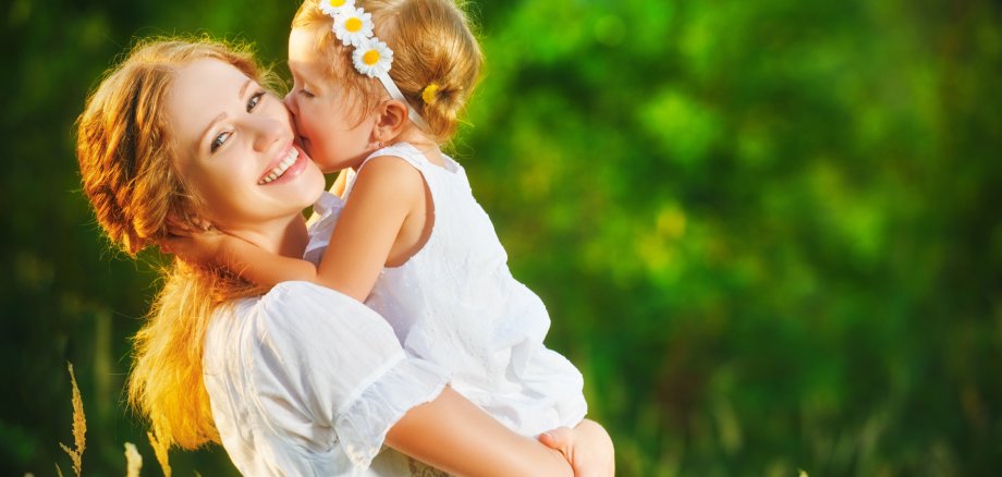 Happy family on summer. little girl child baby daughter hugging and kissing mother